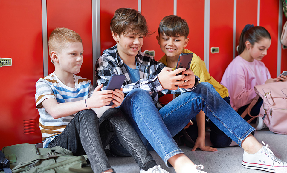 Schüler sitzen in der Schule und hantieren mit ihren Handys.