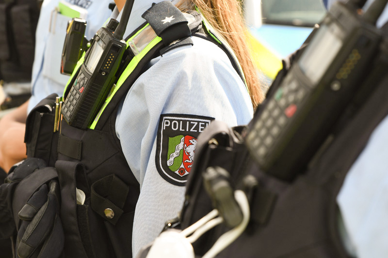 A police officer in uniform and with a radio during a briefing.