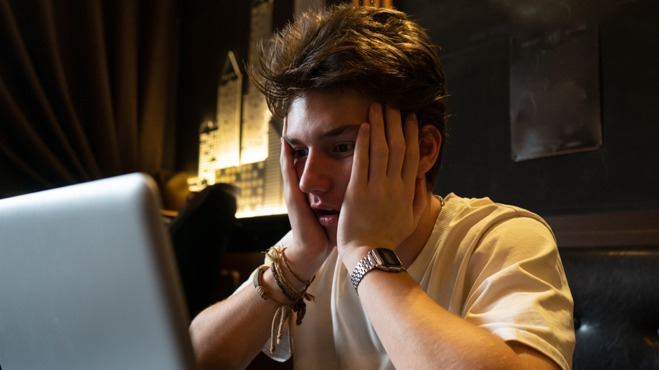 Desperate teenager sits in front of a laptop.