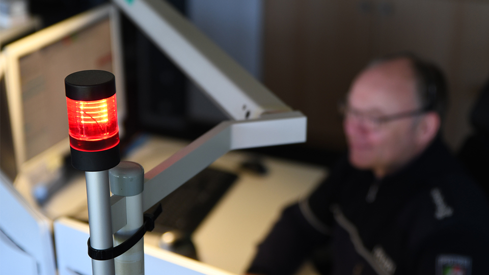 red glowing lamp on a control center with a police officer in the background