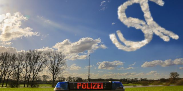 Polizeiwagen mit Leuchtschrift "Polizei" sowie dahinter ein strahlend blauer Himmel mit den Buchstaben s und t aus Wolken gezeichnet. 