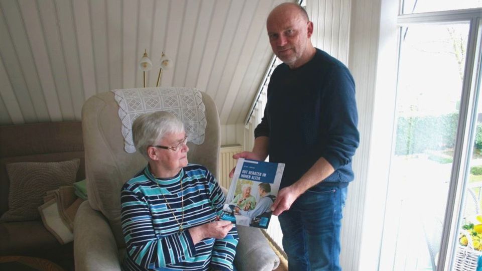 Kriminalhauptkommissar übergibt Broschüre an Seniorin