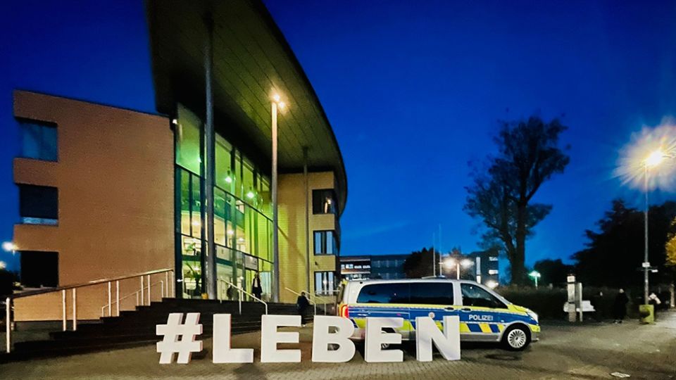 Der Schriftzug #Leben mit Buchstaben aus Pappe steht vor dem Gebäude der kaufmännischen Schulen in Rheine. Dahinter ist ein Polizeiwagen zu sehen.