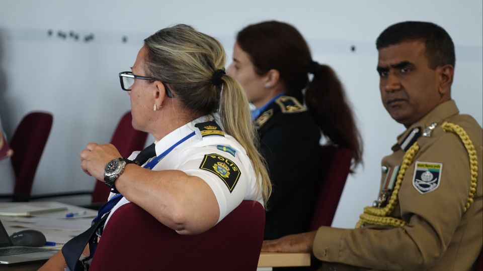 Three seminar participants sit on chairs and listen.