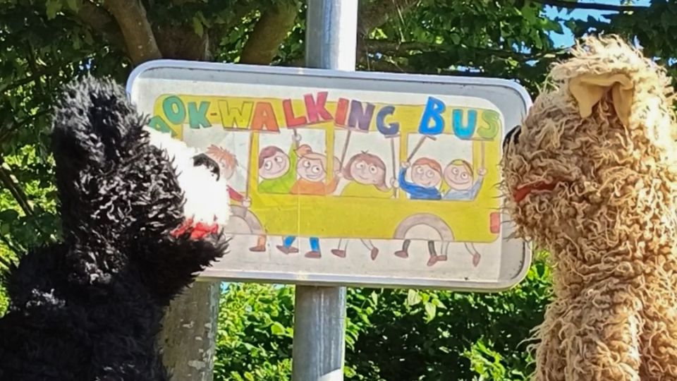 Zwei Handpuppen schauen auf ein Straßenschild.
