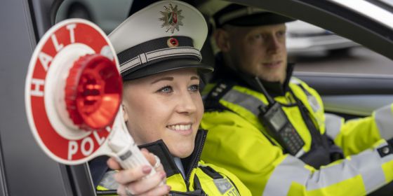 Polizisten im Streifenwagen mit Anhaltekelle