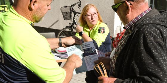 Zwei Kollegen der Verkehrsunfallprävention der Kreispolizei Steinfurt informieren einen Bürger darüber, wie er Fahrradunfälle vermeiden kann.